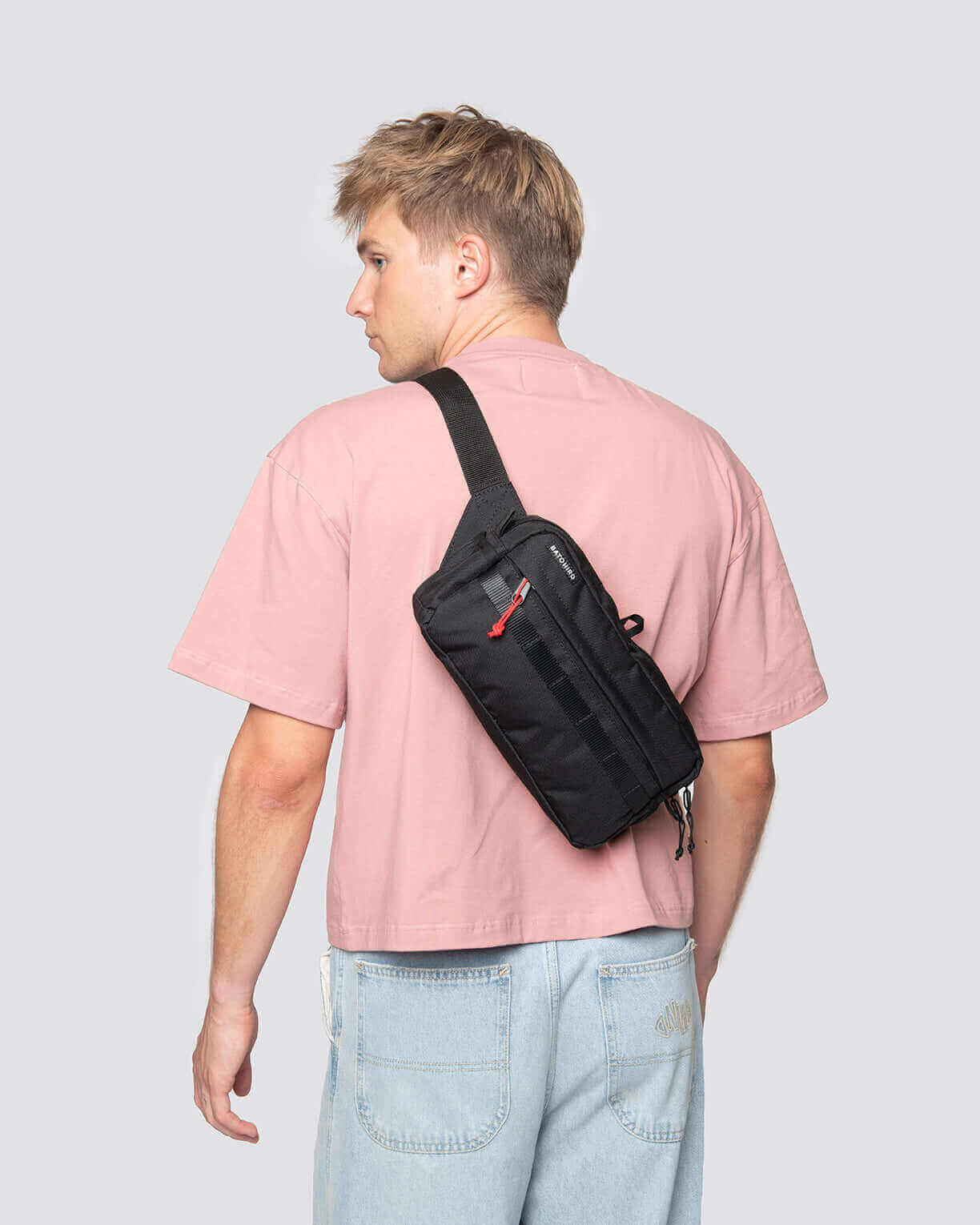 Mann mit schwarzer crossbody reisetasche auf dem Rücken, im Überblick in modischer Kleidung.