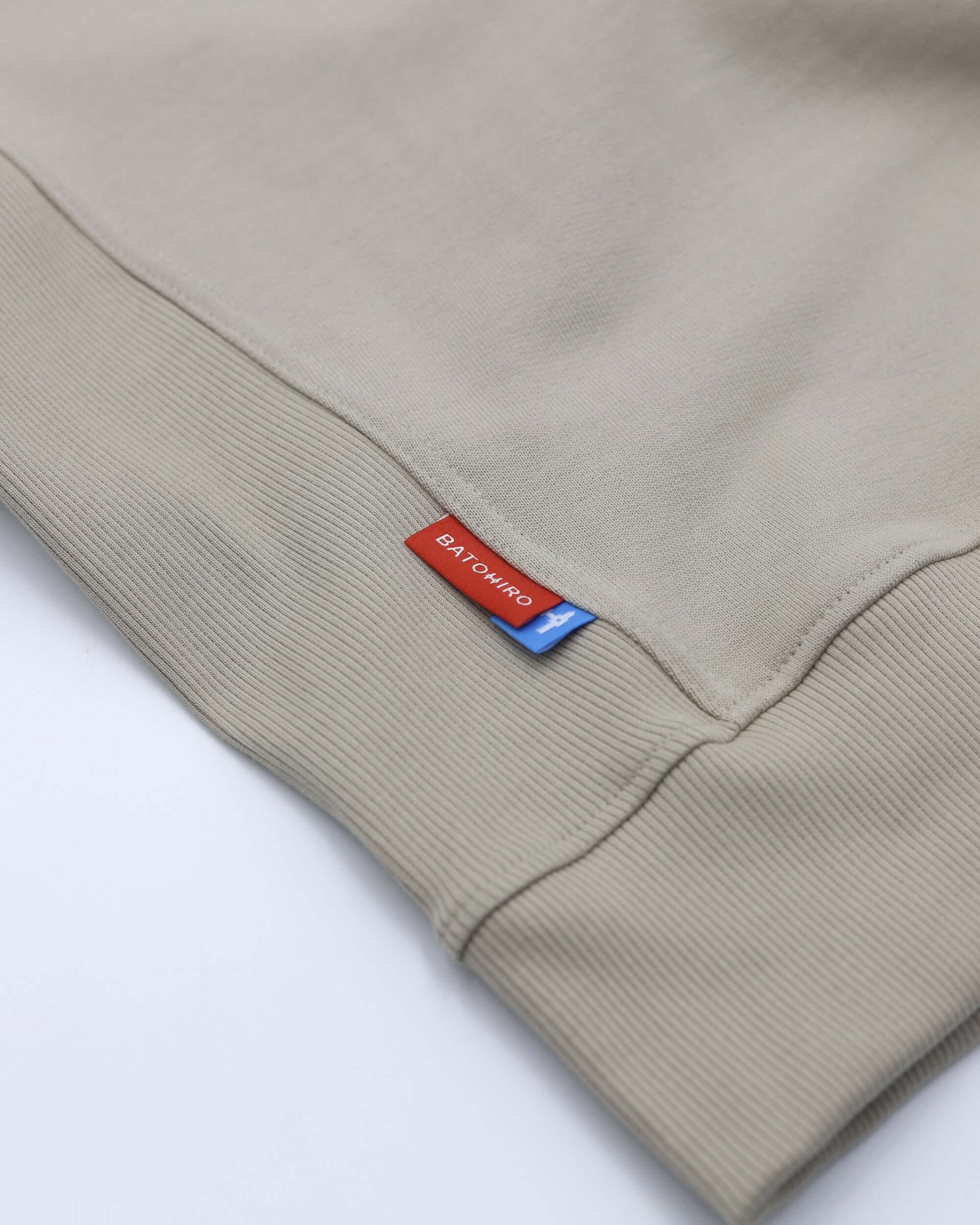 Béžová mikina crewneck Batohiro s detailem na manžetách a štítkem.