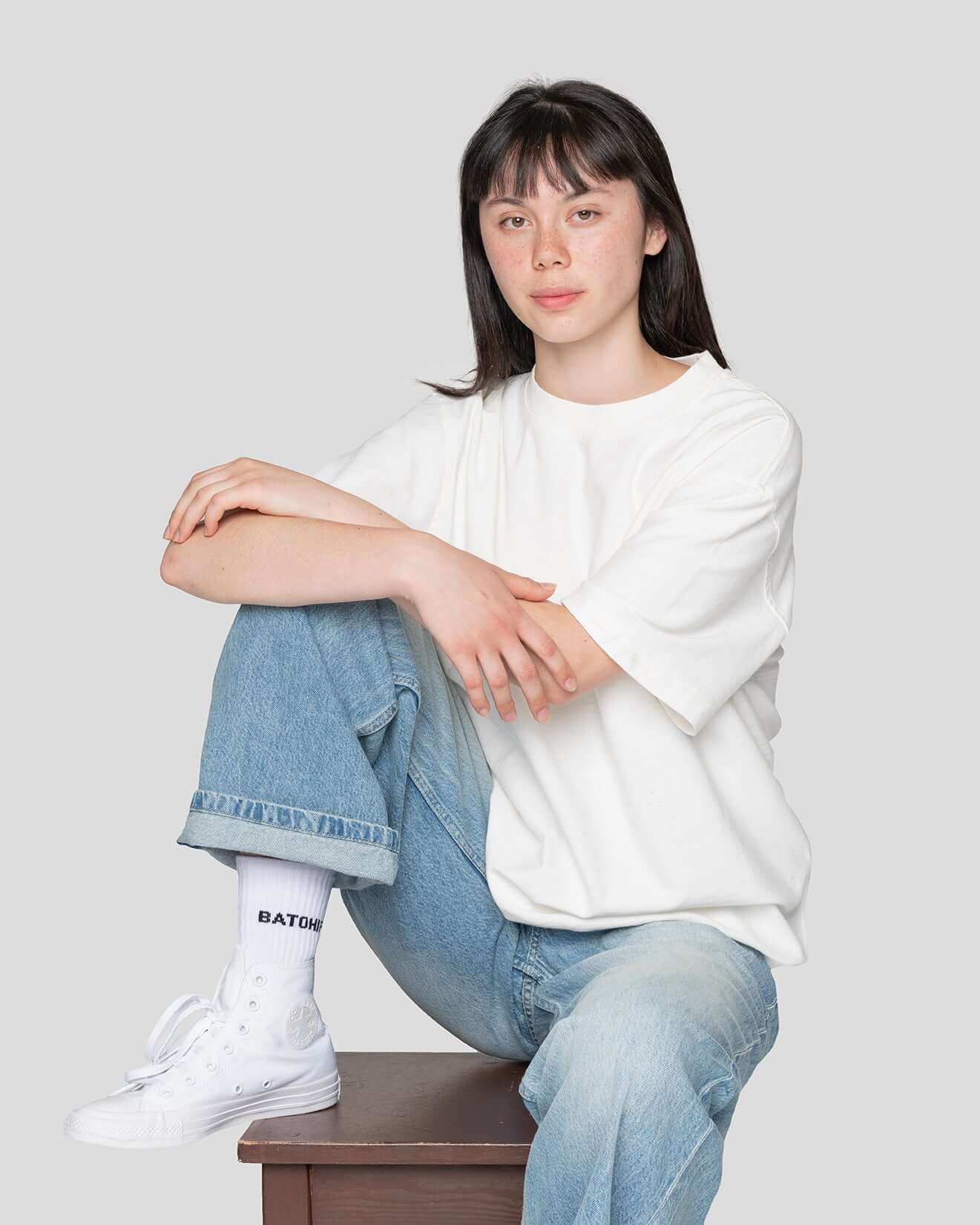 Model wearing a white oversized t-shirt and stylish socks, showcasing a relaxed and modern outfit.
