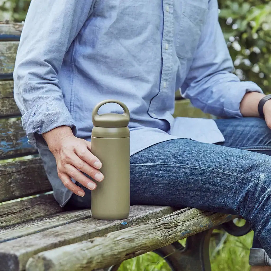 DAY OFF Tumbler 500ml held by a man sitting on a wooden bench outdoors.