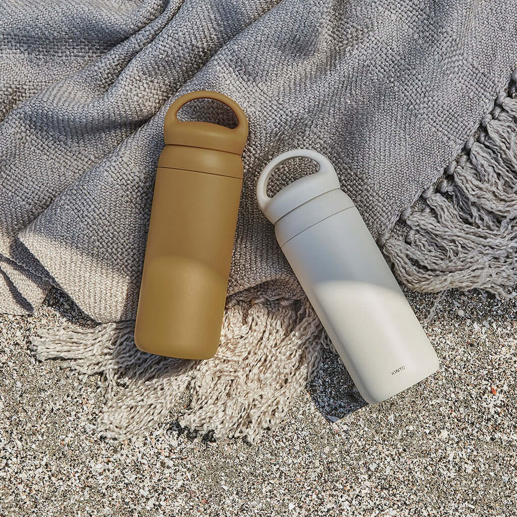 DAY OFF Tumbler 500ml in brown and white colors on a textured blanket by the beach.