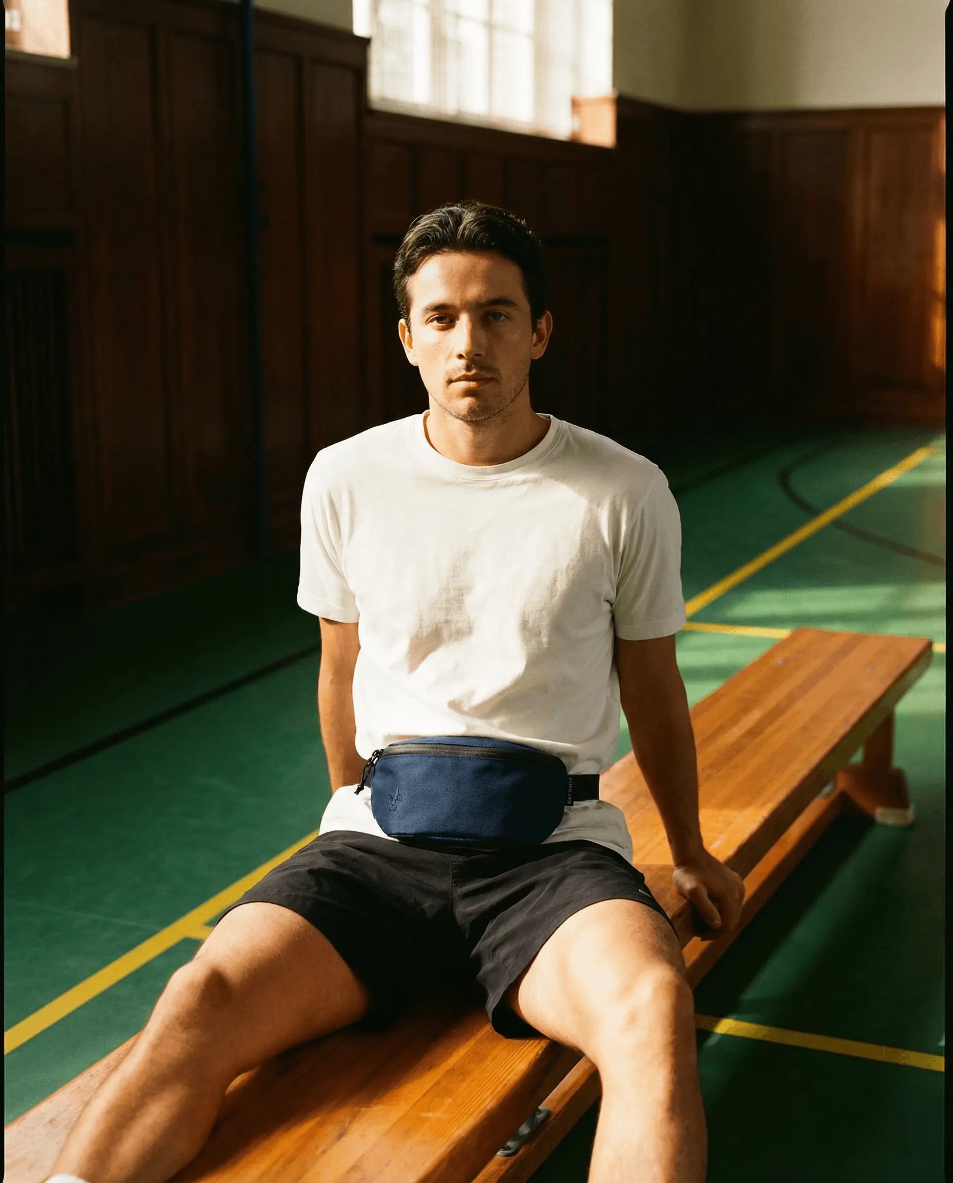 Sora 2.0 - Navy Blue worn by a man sitting on a bench in a gym, showcasing its minimalist design and practicality.
