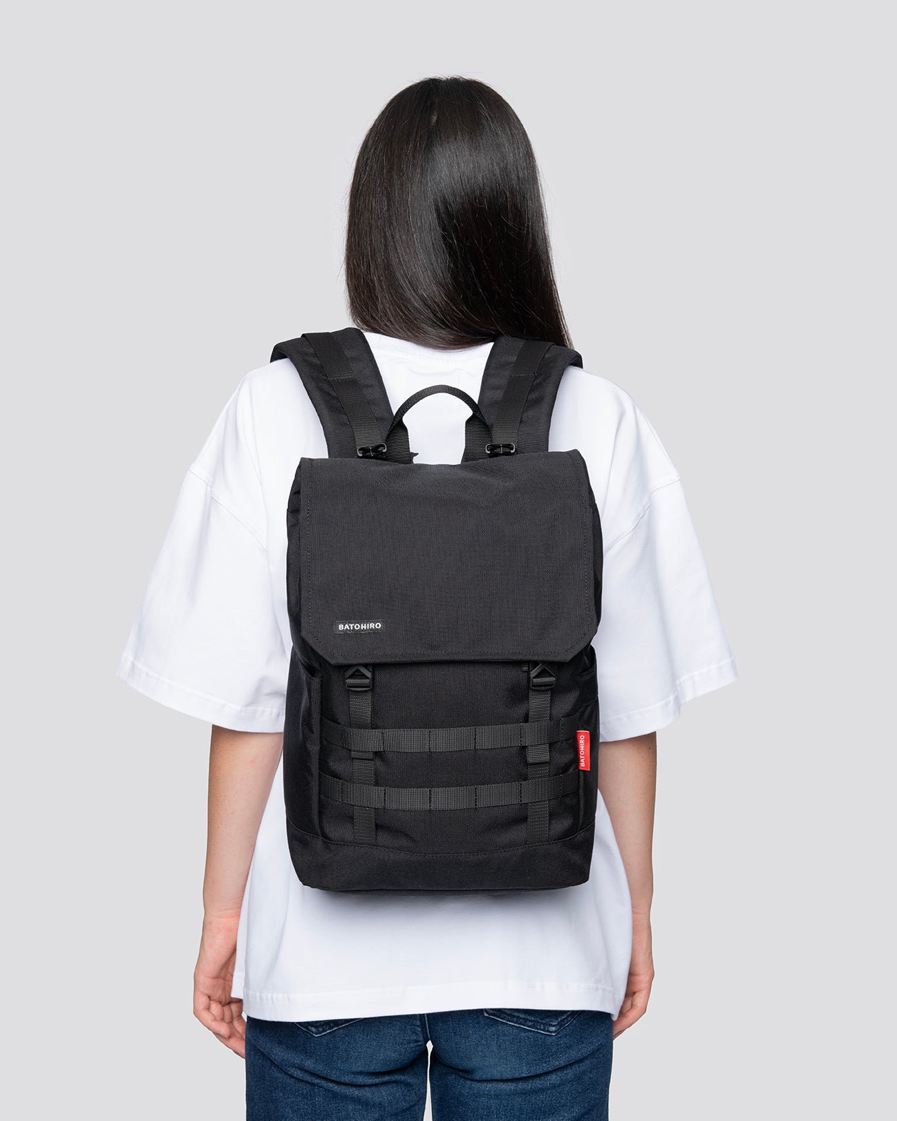 Person wearing a sleek black backpack over a white shirt and jeans, showcasing a stylish and versatile design for everyday use.