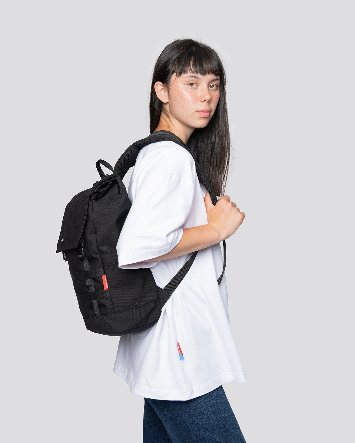 Person wearing a Minato Lite black backpack, showcasing its compact design and flexible straps ideal for everyday use.